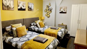 A room with two beds, a chandelier, artwork on the walls, and a wardrobe. - Roof Terrace Beach at end of road, Private Parking (Portsmouth)