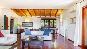 Ein geräumiges Wohnzimmer mit Holzboden, einem weißen Sofa, einem Couchtisch und einem Essbereich mit Tisch und Stühlen.