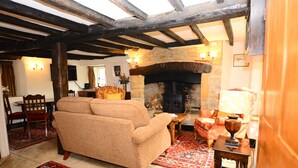 A cozy living room with a fireplace, wooden beams, and a sofa.
