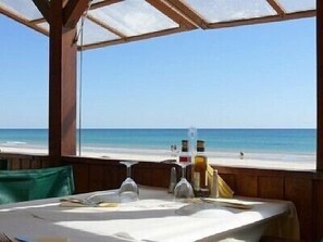 Mesa dispuesta para comer con vista a la playa y al océano.