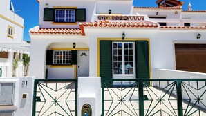 Un bâtiment blanc avec des volets verts et un toit recouvert de tuiles.