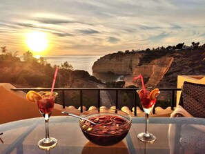 Un tavolo con due bevande e una ciotola di cibo, con vista su un paesaggio costiero con scogliere e l'oceano.