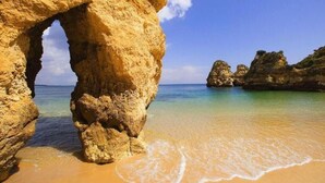 Eine natürliche Felsformation mit einem deutlichen Steg, der zu einem Sandstrand führt.