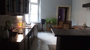 Une cuisine équipée d’une cuisinière, d’un évier et de placards. Une fenêtre laisse entrer la lumière naturelle et une plante est posée sur une petite table.