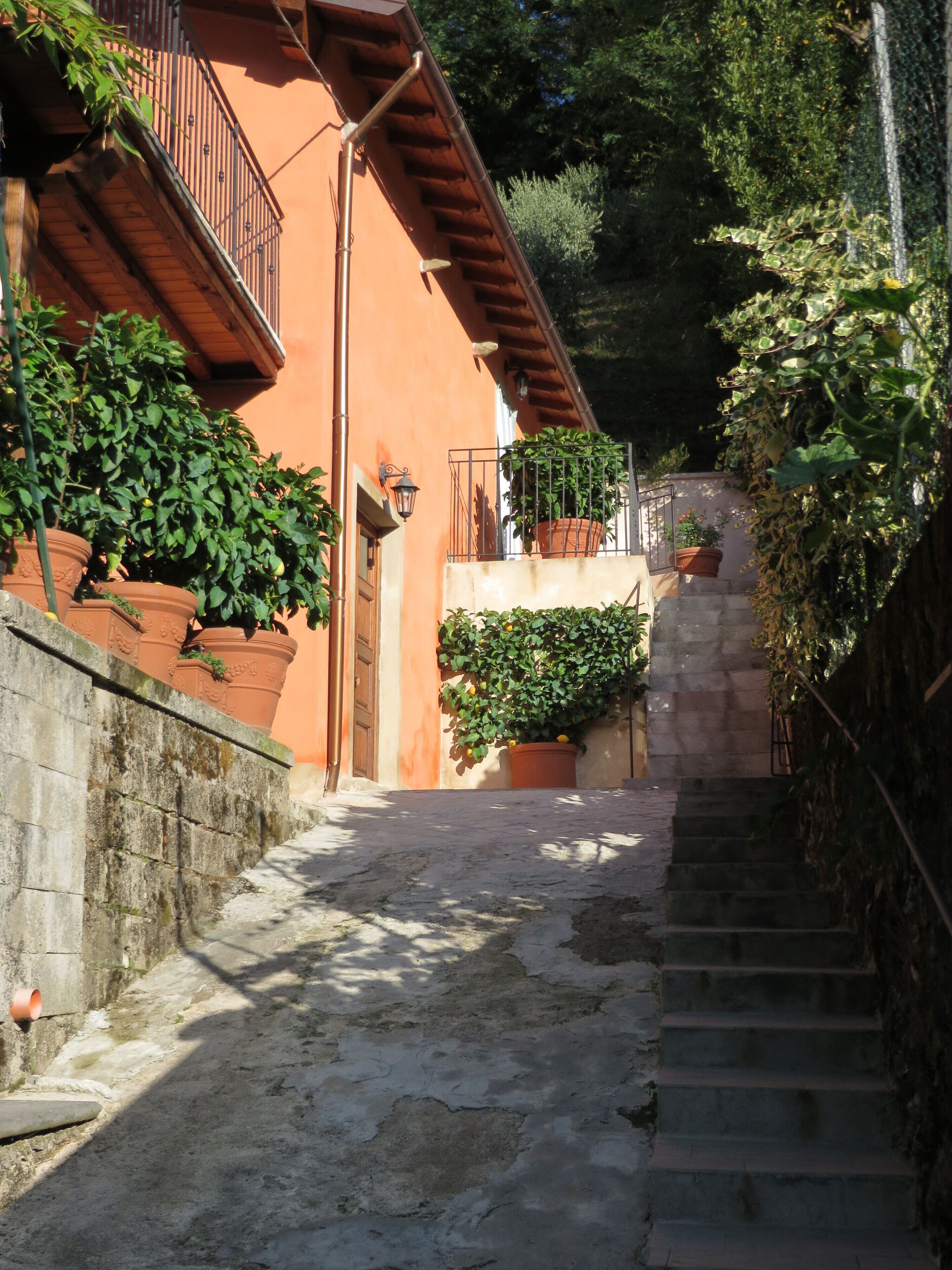 A narrow stone staircase leading up to a building with terracotta walls and a wooden balcony.