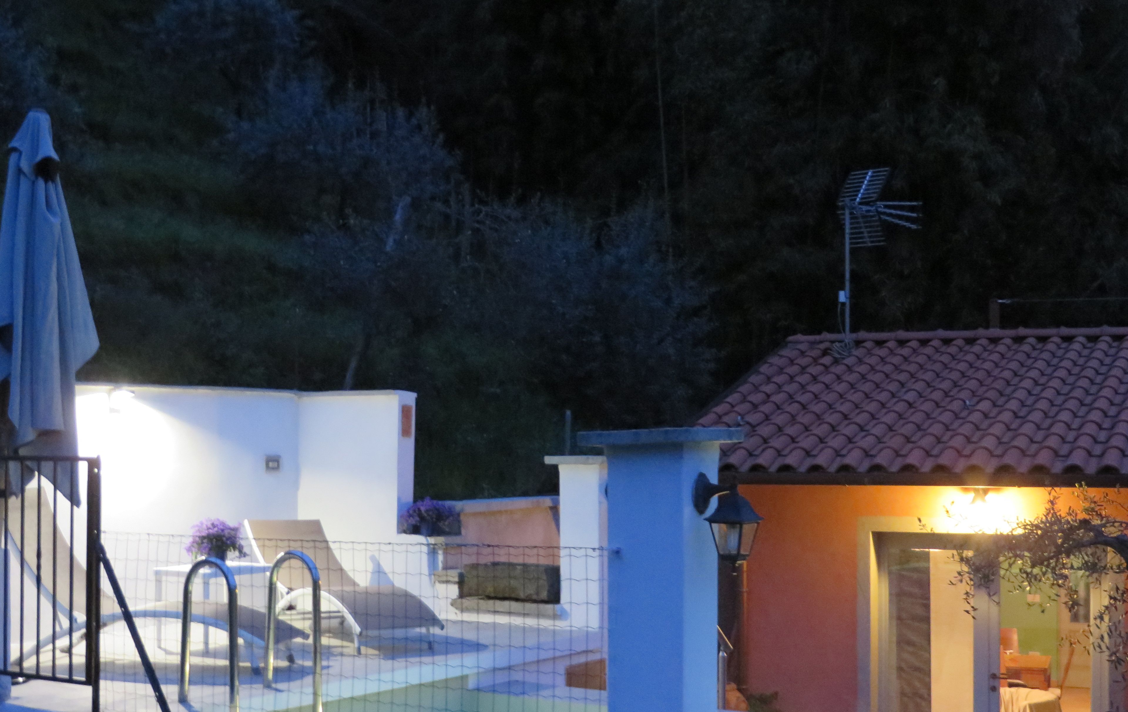 Zona residencial con piscina, terraza techada y un pequeño edificio de techo con tejas.