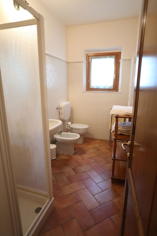 Une salle de bain comprenant des toilettes, un bidet et un espace douche.