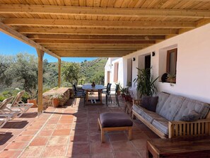 A covered patio with a table and chairs, a cushioned bench, and potted plants. - Spacious 4 Bed villa with pool and fantastic views!! (Frigiliana)