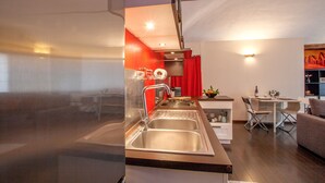 Una cocina moderna con electrodomésticos de acero inoxidable, un comedor con mesa y sillas, y una sala de estar con sofá y mesa de centro.
