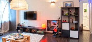 Una sala de estar con televisor de pantalla plana, chimenea, estantería y una guitarra.
