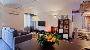 Una sala de estar moderna con un sofá, una mesa de comedor con un frutero, una chimenea y una estantería.