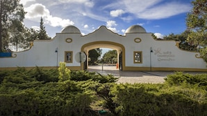 An entrance with a white facade, two domed structures, and a sign for a golf and country club.