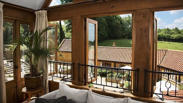 Une pièce dotée de grandes fenêtres, d’un balcon en bois et d’une plante en pot.