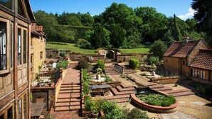 Une cour intérieure avec des allées pavées, une fontaine centrale et de la verdure tout autour.
