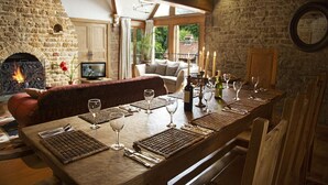 Un coin repas agrémenté d’une cheminée en pierre, de meubles en bois et offrant une vue sur la verdure environnante.