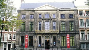 A historic building with a symmetrical facade, large windows, and two prominent red banners. - Gorgeous canal house in The Hague city (Den Haag)