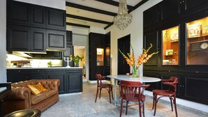 A modern kitchen with dark cabinetry, a dining area with a round table and chairs, and a chandelier. - Gorgeous canal house in The Hague city (Den Haag)