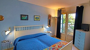 Un dormitorio con cama, cómoda, lámpara y televisor.