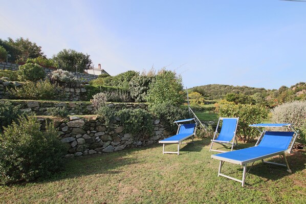 Un jardín con muros de piedra y sillones azules.