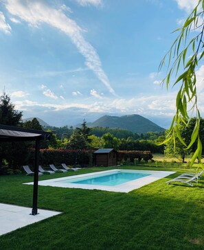 Una piscina con sillas de descanso, un cobertizo de madera y vistas a montañas.