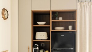 A compact kitchen with a black refrigerator, wooden shelves, a toaster, and a kettle. - Enjoy our cozy 40m² diaphanous loft. Comfort and relaxation. (Aia)