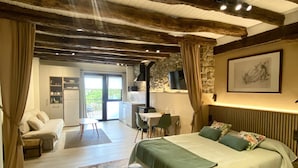 A bedroom with a bed, a desk, a stone wall, and a view of the outdoors. - Enjoy our cozy 40m² diaphanous loft. Comfort and relaxation. (Aia)
