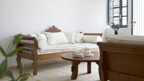Ein gemütliches Zimmer mit einer Holzsofa, einem kleinen runden Tisch mit Teekanne und Teller sowie einem Fenster mit Ausblick.