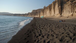 Ein Strand mit einer felsigen Klippe und Fußabdrücken im Sand.