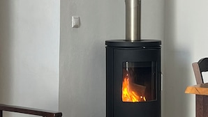 Ein modernes Zimmer mit einem schwarzen Kaminofen, einer hölzernen Bank und einem kleinen Tisch.