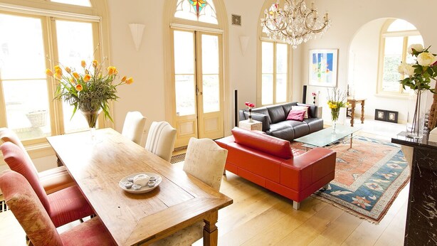 A spacious living room with a wooden dining table, red sofa, and a chandelier. - Exclusive location in an oasis of tranquillity in Hoorn (near Amsterdam).  (Hoorn NH)