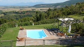 Ein Poolbereich mit Blick auf die Landschaft, darunter Hügel und ein Dorf in der Ferne.