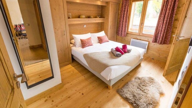 Une pièce en bois avec un lit, un miroir et un tapis en fourrure.