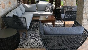 An outdoor patio area with a sofa, chairs, and a small table.