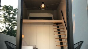 A modern interior with a loft bed, a staircase, and a seating area.