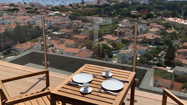 Mesa de madera para dos personas con vista a un pueblo costero y al mar.