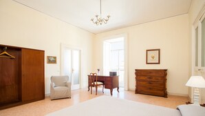 Un dormitorio con cama, escritorio, silla, cómoda y perchero.