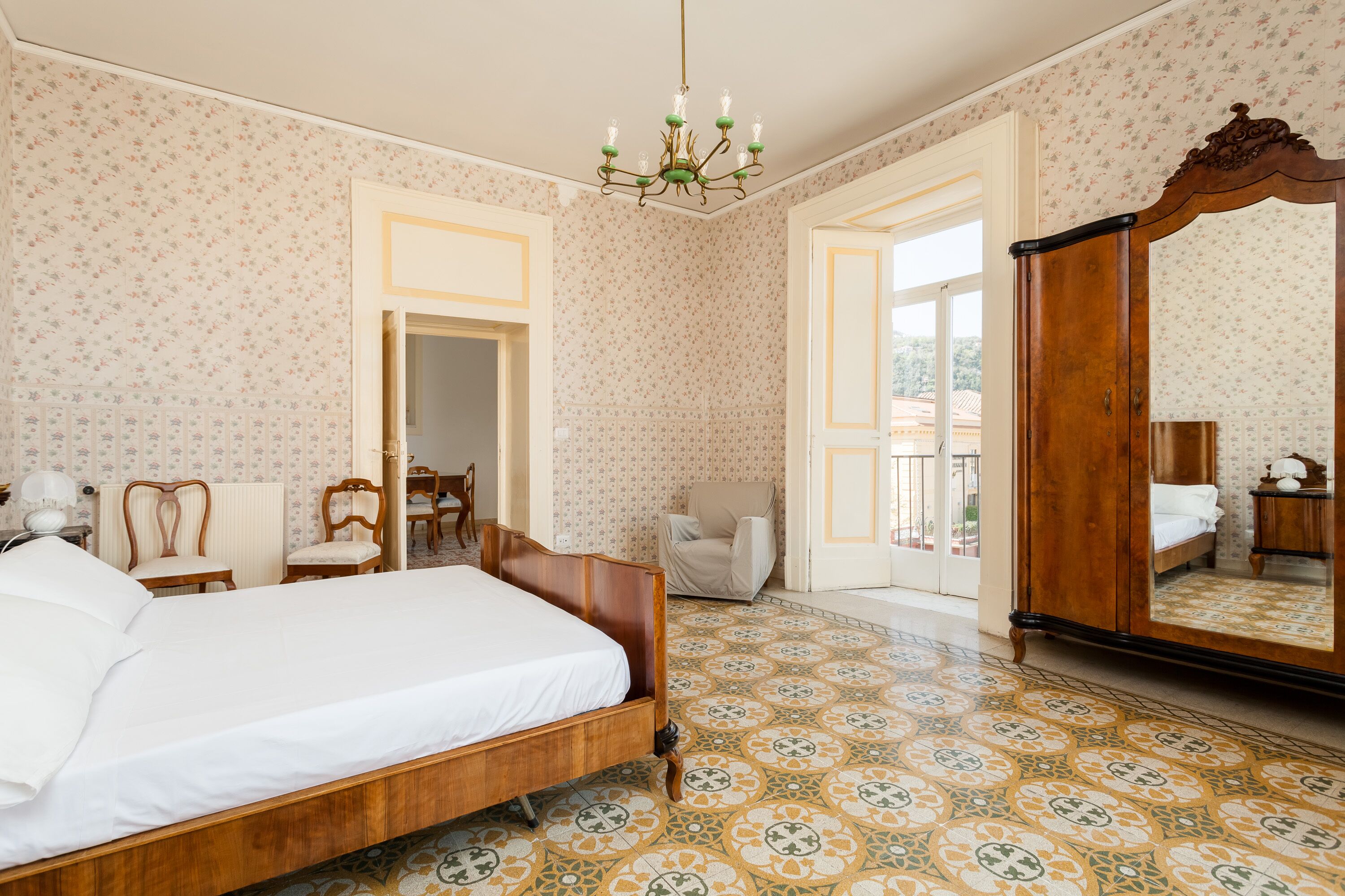Quarto com cama de madeira, uma cadeira, escrivaninha e guarda-roupa.