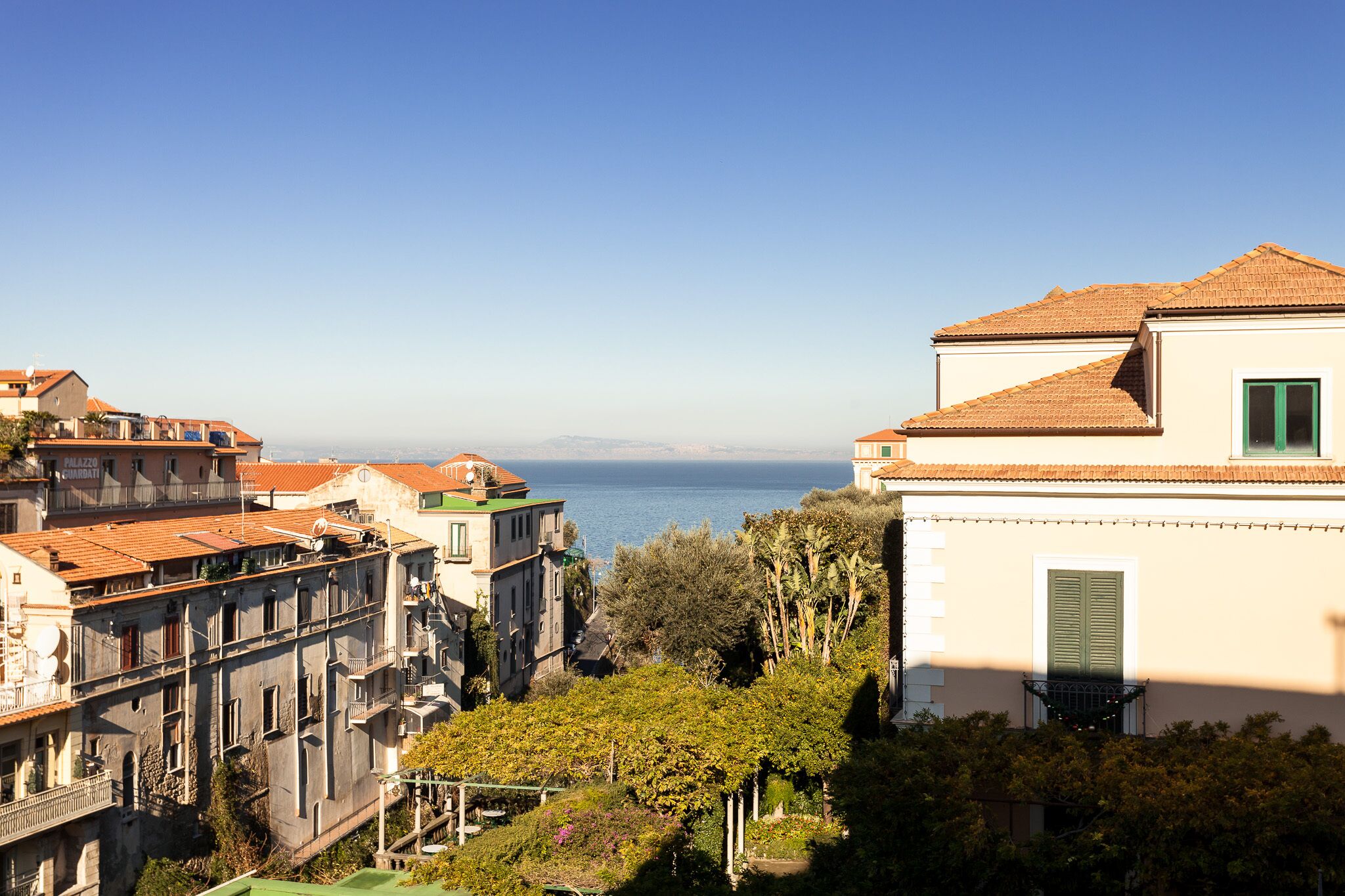 A coastal building with a tiled roof, a balcony, and a view of the sea.