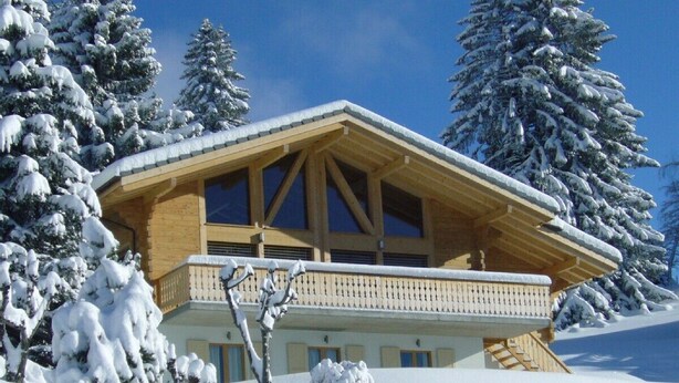 A wooden chalet with a balcony, surrounded by snow-covered trees. - Luxury Modern Swiss Chalet - Spectacular Panoramic Views - 200m From Piste (Gryon)