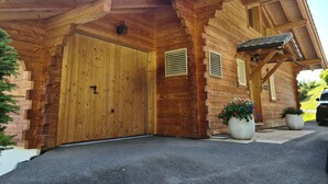 A wooden cabin with a large wooden door, two small windows with shutters, and a covered porch area. - Luxury Modern Swiss Chalet - Spectacular Panoramic Views - 200m From Piste (Gryon)