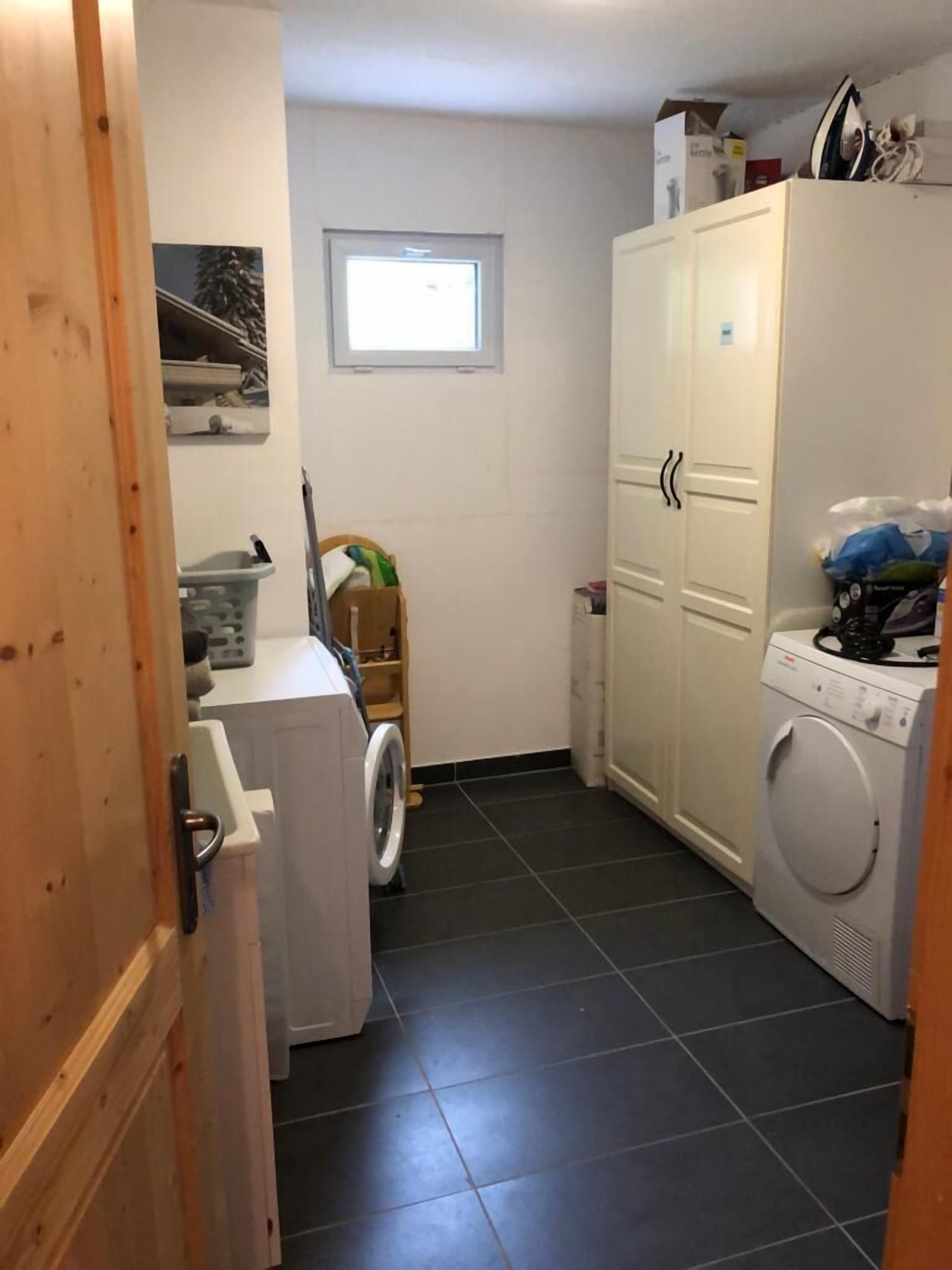 A laundry room with a washing machine, dryer, and a small window.