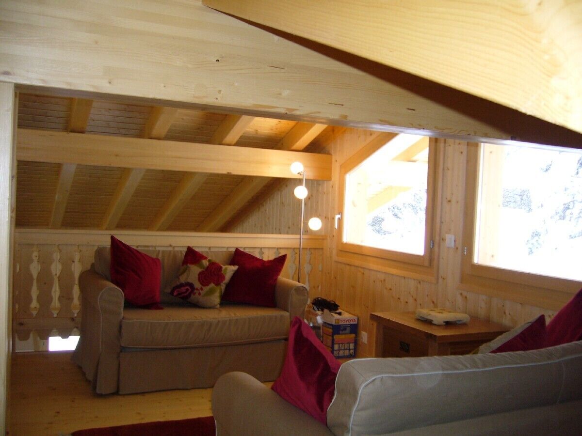 Interior acogedor de una cabaña de madera con un sofá, sillones, una mesita y una ventana con vistas.