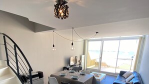 Un espacio habitable moderno con escalera, comedor y sofá.
