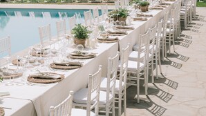 A long dining table set with white chairs and a pool in the background. - Villa Santarsa, 31 people, magnificent views and private pool, no neighbors (Sansepolcro)