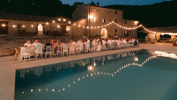 A poolside dining area with stone buildings and string lights. - Villa Santarsa, 31 people, magnificent views and private pool, no neighbors (Sansepolcro)
