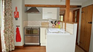 A compact kitchen with a stove, oven, and white cabinets. - Lovely Devon barn, near Exeter, set in 15 acres of countryside (Crediton)
