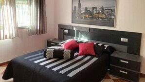 Ein modernes Hotelzimmer mit einem großen Bett, einem Stadtbild, einem Nachttisch und einem Schreibtisch mit Schubladen.