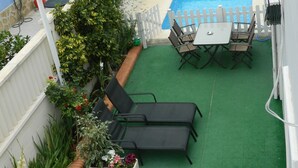 Ein Poolbereich auf dem Dach mit grüner Kunstrasen, einem weißen Zaun und einem Pool.