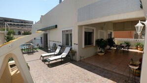 Eine sonnendurchflutete Terrasse mit zwei Liegestühlen, einem kleinen Billardtisch und Topfpflanzen.
