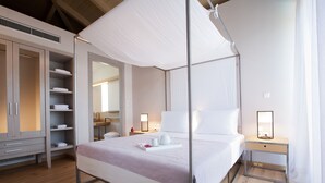 A neatly arranged bedroom with a canopy bed, a wardrobe with shelves, a bedside table with a lamp, and a nightstand. - Aggelos Brand New Exclusive Villa with Private Pool (Agrikies Villas) (Lefkada)